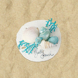 A round refrigerator magnet resembling a sand dollar with green and white coral and blue sea spray on a sandy background.